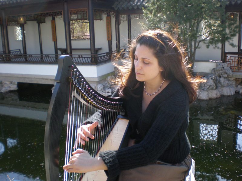 Mia Theodoratus playing the harp in a garden on Staten Island